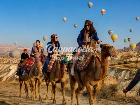 Turisti a dorso di cammello tra le rocce della Cappadocia