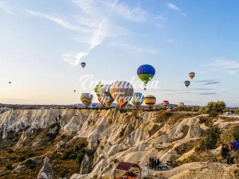Gün doğumunda Kapadokya vadileri üzerinde süzülen renkli balonlar
