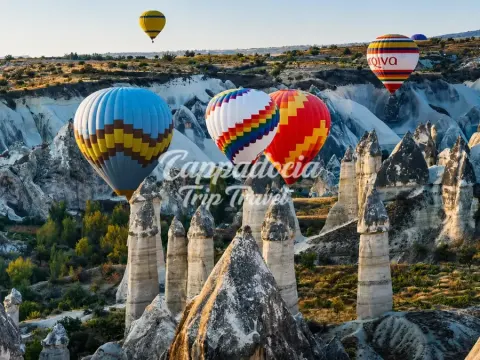 Gün doğumunda Kapadokya vadileri üzerinde süzülen rengarenk sıcak hava balonları
